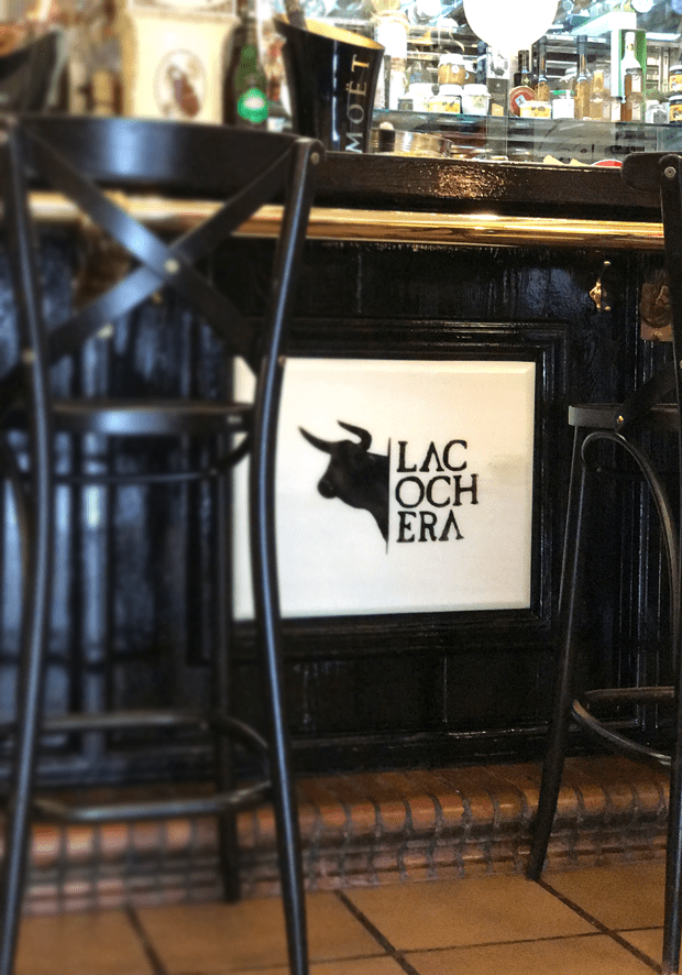 Logo de La Cochera sobre mármol en la barra